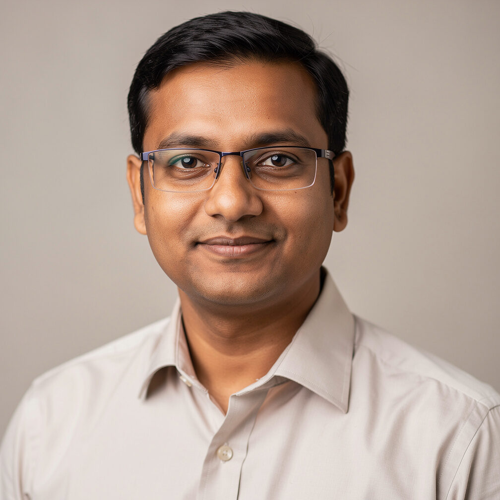 Headshot of an Indian man compliance officer with glasses smiling